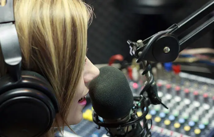 A woman with headphones on talking into a microphone.