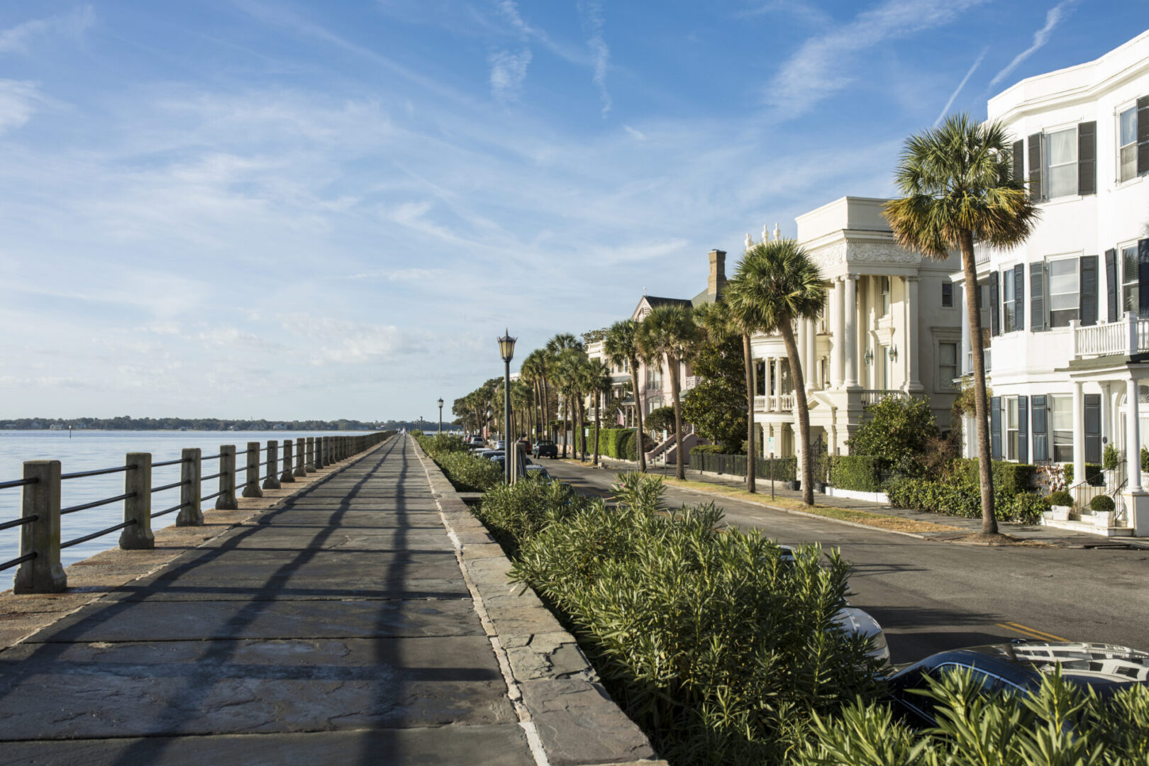 A road with trees and buildings next to the water.